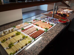 Un bufé con diversos quesos, carnes y frutas.