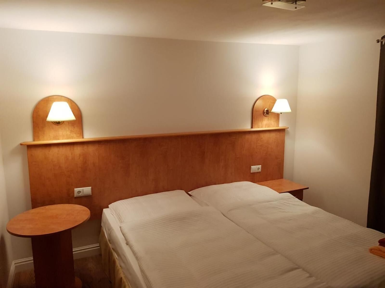 A double bed with a wooden headboard and two bedside lamps.