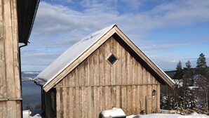 A wooden barn with a snow-covered roof, a small window, and a door.