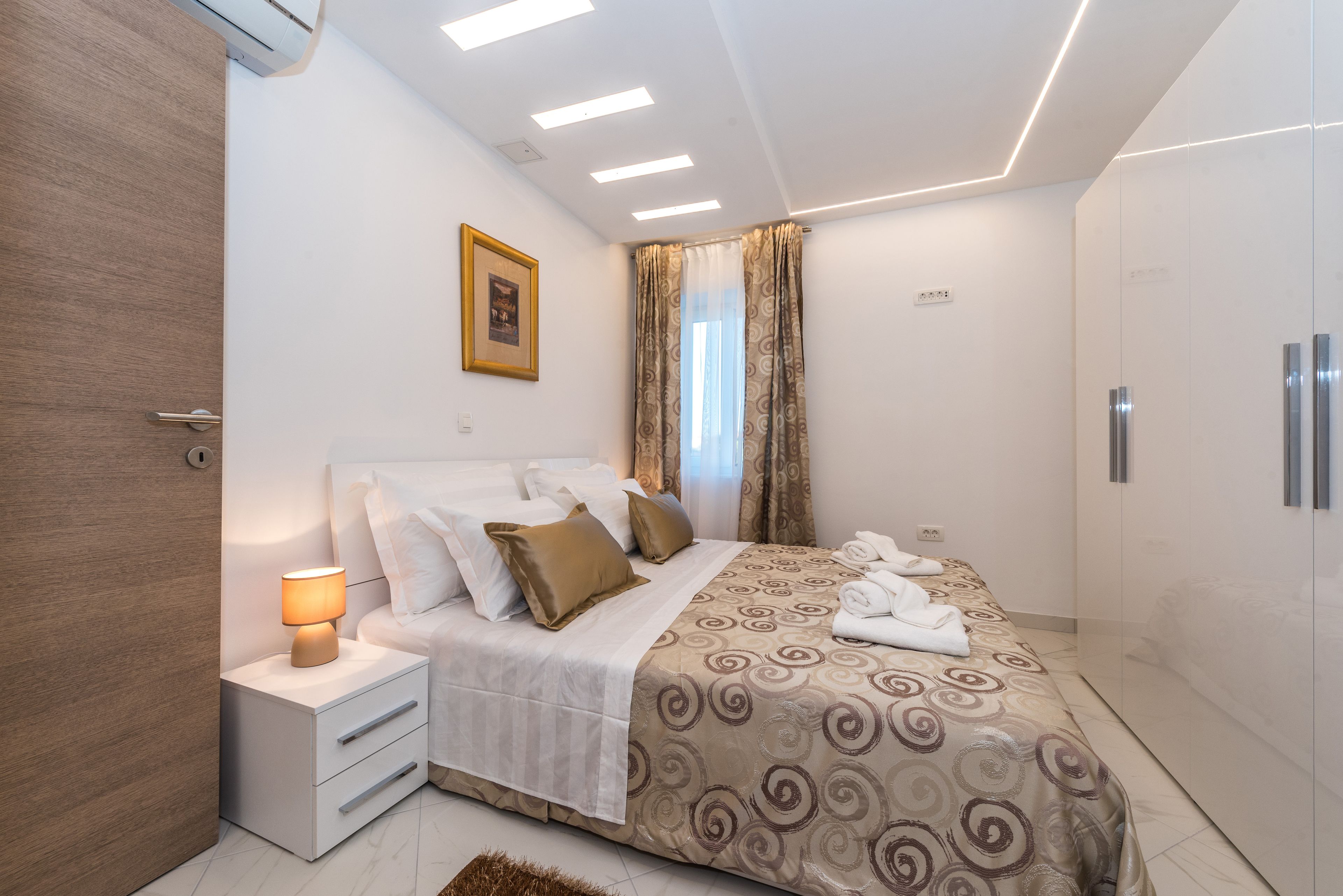 A modern bedroom with a bed, bedside lamp, and a wardrobe.
