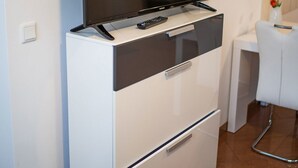 Une petite cuisine équipée comprenant un micro-ondes encastré, un petit réfrigérateur et un téléviseur à écran plat fixé au mur.