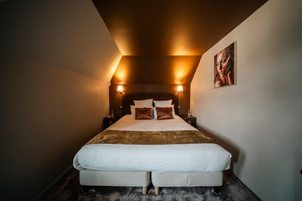 A bedroom with a large bed, two bedside tables, and wall-mounted lamps.