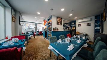 En restaurant med borde dækket til spisning, et barområde og hylder fyldt med flasker.