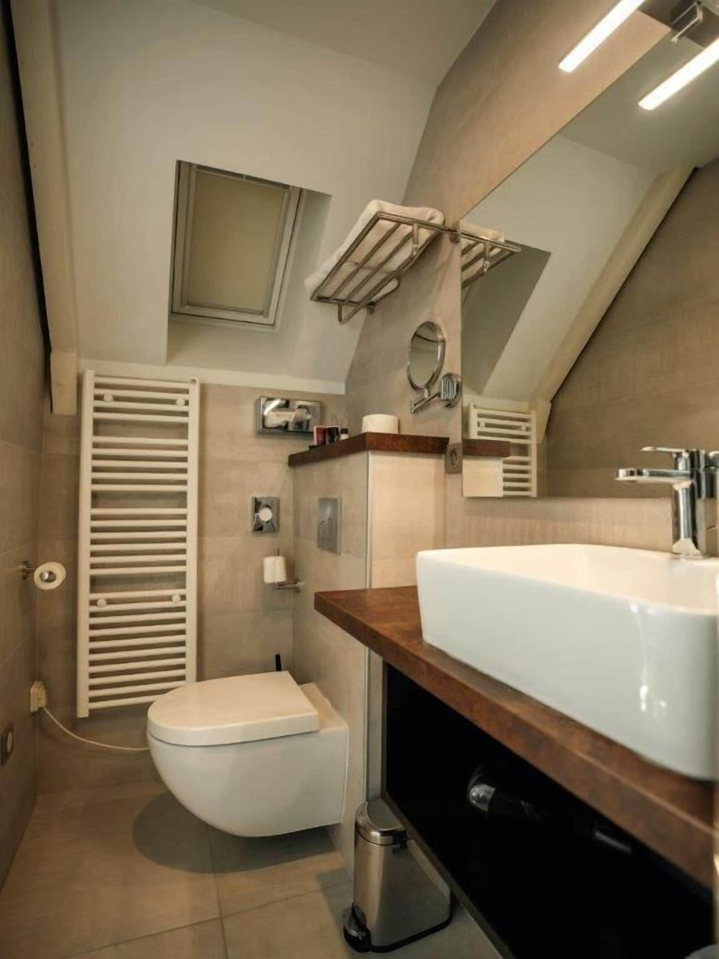 A modern bathroom with a white sink, toilet, and towel rack.