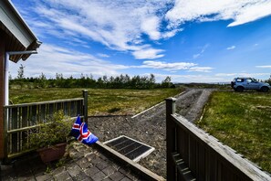 A rural driveway leading to a house with a flag on the gate. - House V10 (Bláskógabyggd)