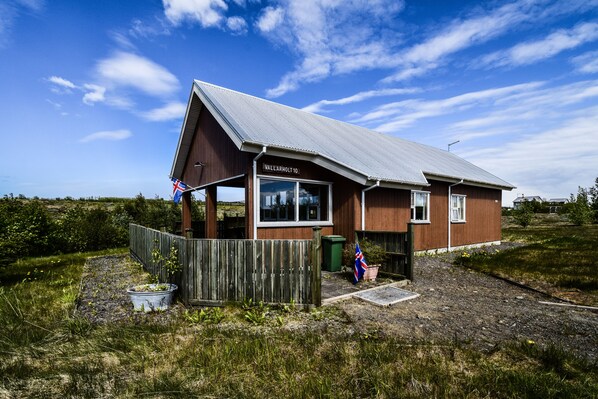 A small, single-story building with a metal roof and a sign reading "VALLARHOLT 10". - House V10 (Bláskógabyggd)