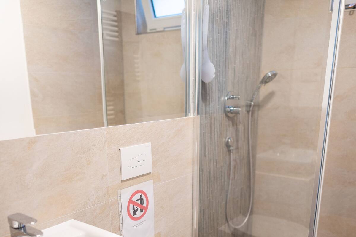 A modern bathroom with a glass-enclosed shower, a white sink, and a toilet.