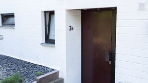 A modern building with a white exterior, a dark door, and a small window.