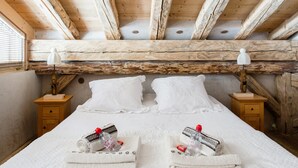 Ein gemütliches Schlafzimmer mit Holzboden, zwei weiße Betten mit Kissen und Nachttische mit Lampen.