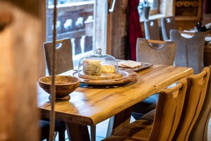 A wooden table with a glass dome cover, a bowl, and a plate with bread. - Chalet sleeps 15 (Montriond)