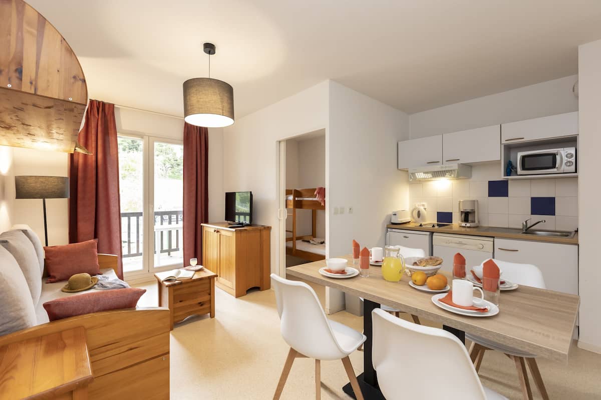 Une cuisine moderne avec des meubles blancs, un four à micro-ondes et un coin repas comprenant une table en bois et des chaises blanches.