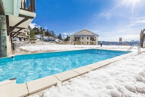 Une piscine entourée de neige, avec un bâtiment en arrière-plan.