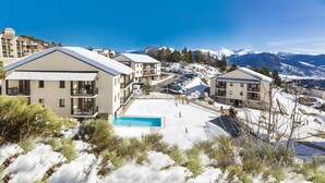 A resort with multiple buildings, a swimming pool, and a snowy mountain backdrop. - Résidence Odalys Mille Soleils (Font-Romeu-Odeillo-Via)