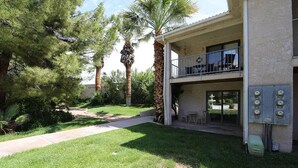 A two-story building with a balcony, a paved walkway, and a well-maintained lawn with trees. - Beautifully Remodeled Condo - Fountain Views (St. George)