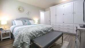 A bedroom with a bed, bedside tables, a bench, a wardrobe, and a mirror. - Beautifully Remodeled Condo - Fountain Views (St. George)