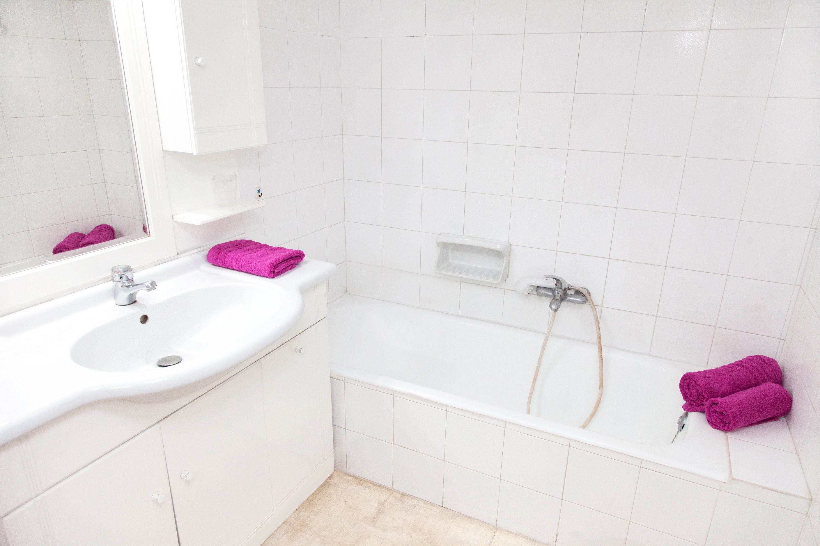 Ein Badezimmer mit einem weißen Waschbecken, einer Badewanne und einem Spiegel.