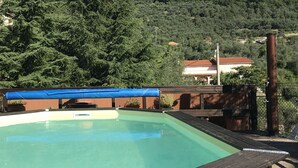 Una piscina con cubierta de madera y una lona azul.