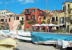 Une rangée de bateaux est amarrée le long d’une promenade, avec des bâtiments aux couleurs vives en arrière-plan.