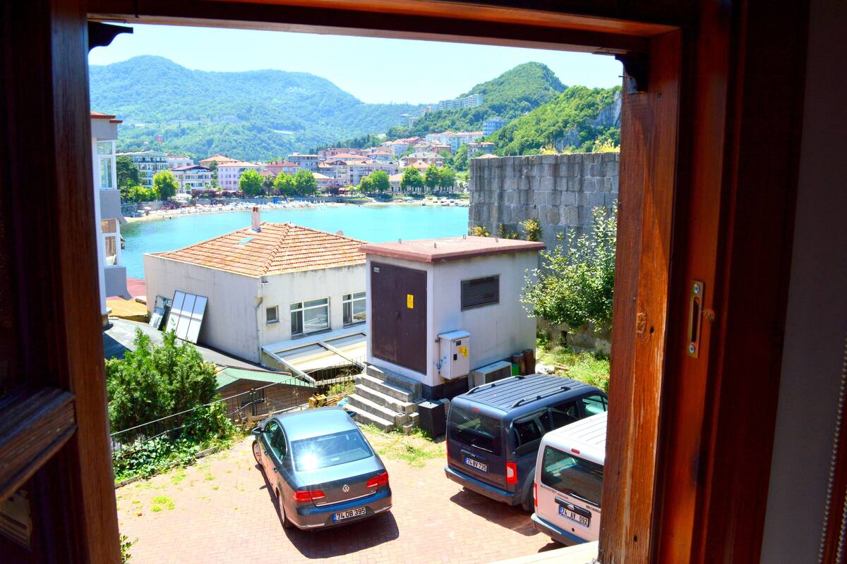 A view from a window overlooking a parking area with a building, a car, and a bus.