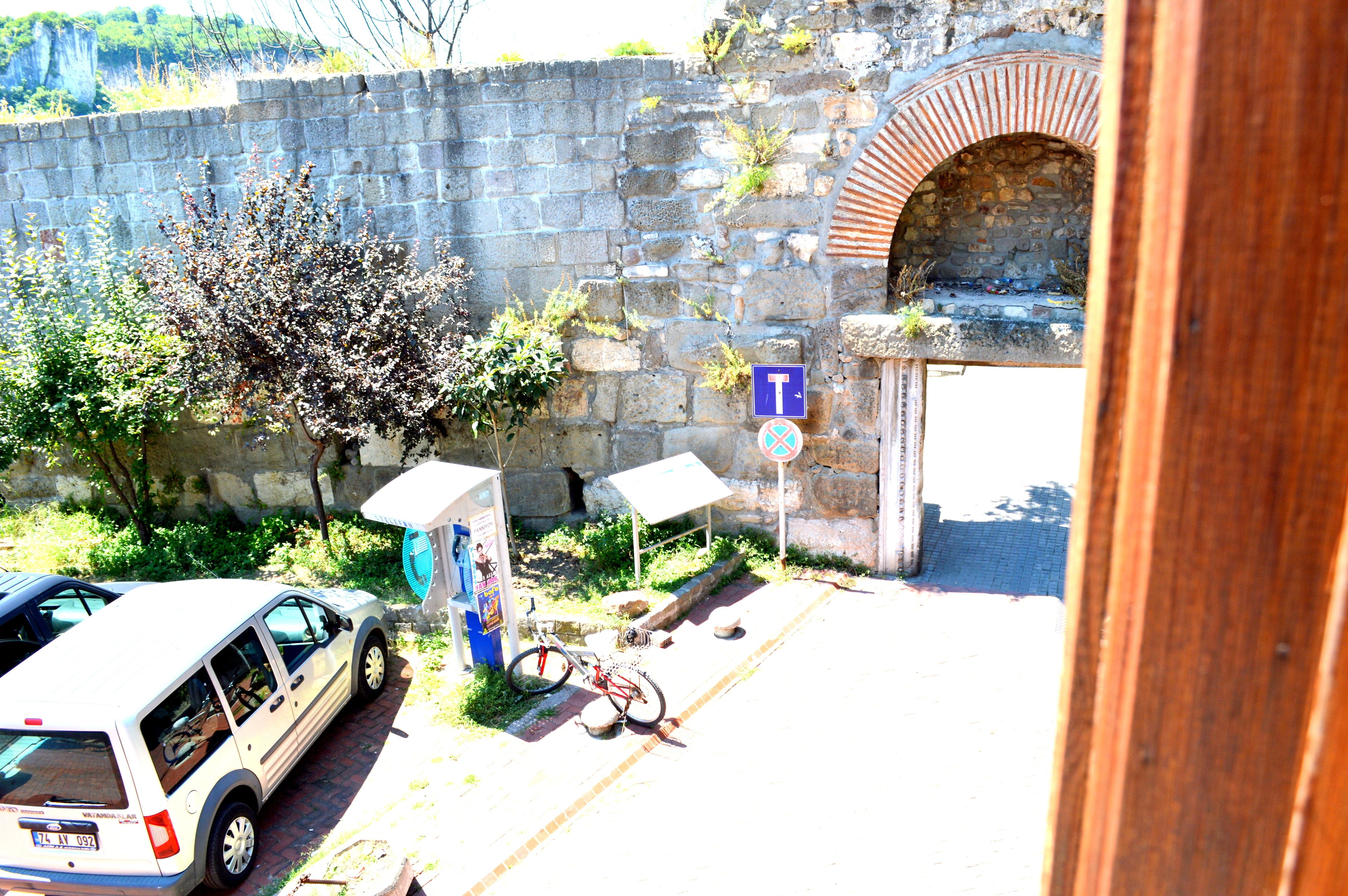 Un muro de piedra con la entrada de un túnel, una bicicleta estacionada y un coche.
