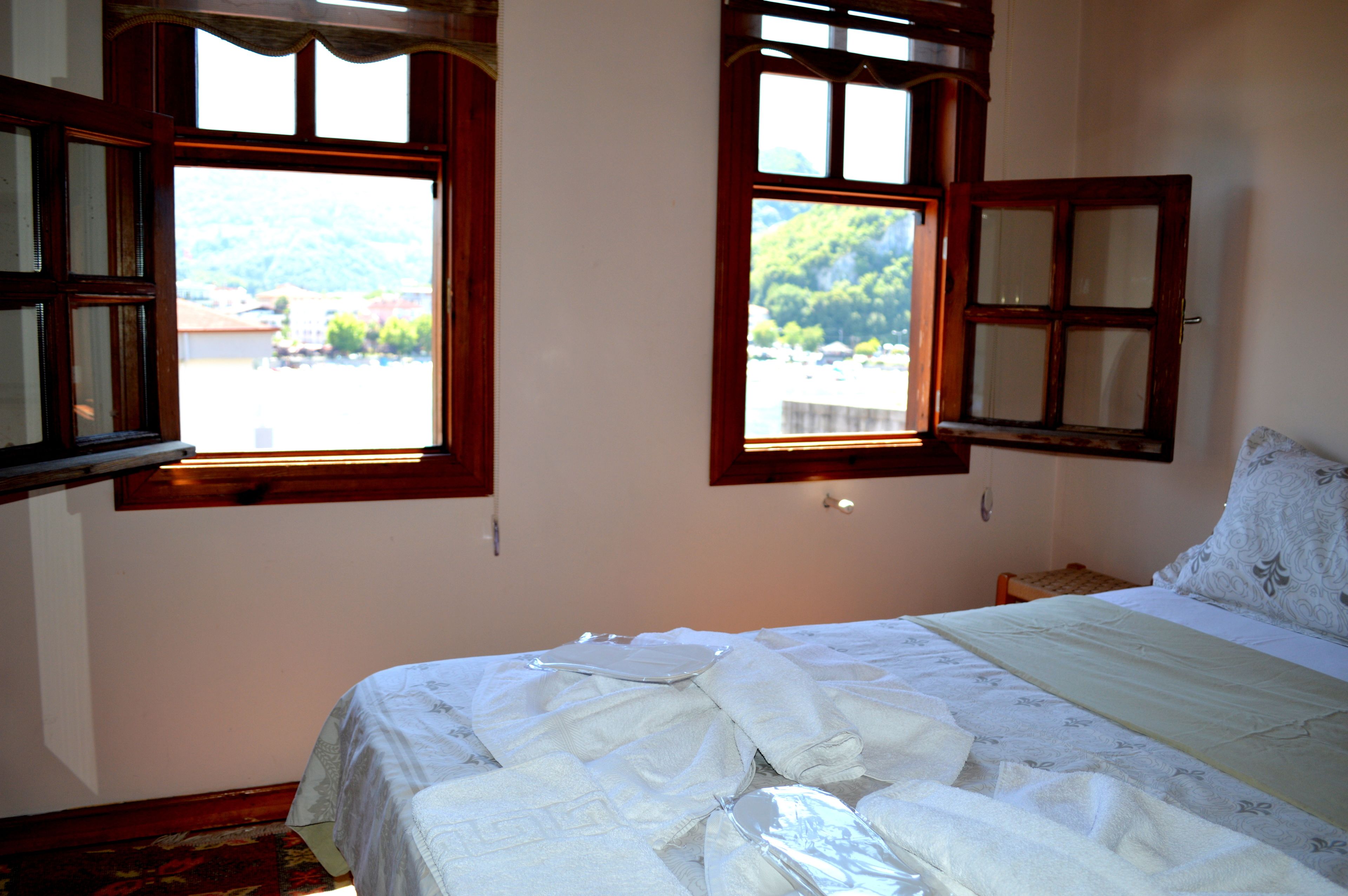 Ein Schlafzimmer mit einem Bett, zwei Fenstern und Blick auf eine Berglandschaft.