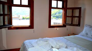Ein Schlafzimmer mit einem Bett, zwei Fenstern und Blick auf eine Berglandschaft.