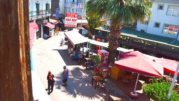 A street view with a Yildiz Cafe and Han Bar, outdoor seating, palm trees, and a pedestrian.