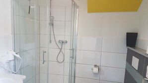 Ein modernes Badezimmer mit einer gläsernen Duschkabine, einer Toilette und einem Waschbecken.