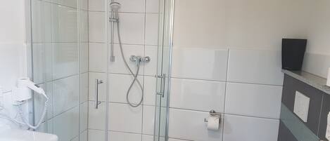 Un baño moderno con ducha envuelta en vidrio, inodoro y lavamanos.