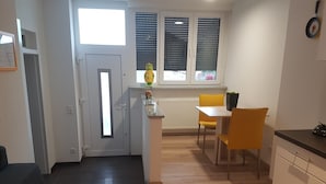Eine kompakte Küche mit Essbereich, einer kleinen Kochinsel und einem Fenster mit Jalousien.
