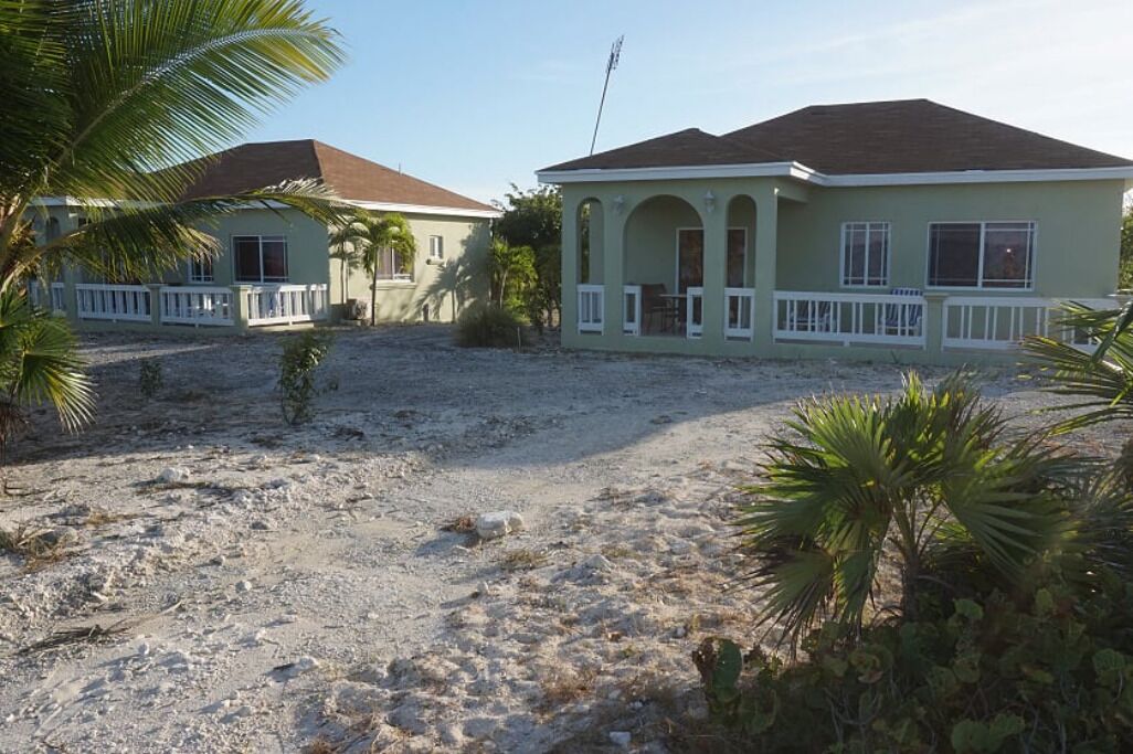 Une maison à deux étages avec une allée en gravier et un petit espace patio.