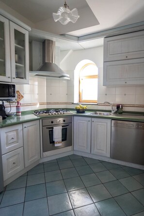 Une cuisine avec des meubles blancs, une cuisinière, un four et un lave-vaisselle.