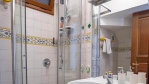 Ein Badezimmer mit einer Duschkabine, einem weißen Waschbecken mit Spiegel und gefliesten Wänden.