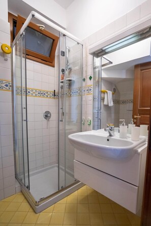 Ein Badezimmer mit einer Duschkabine, einem weißen Waschbecken mit Spiegel und gefliesten Wänden.