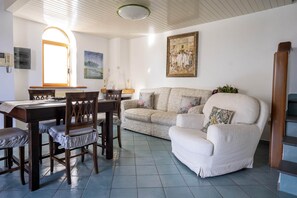 Ein Wohnzimmer mit Esstisch, Stühlen, einer Couch und einem Gemälde an der Wand.