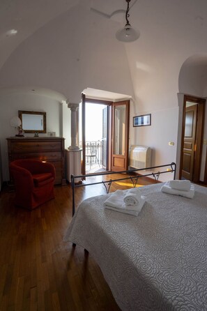 Une chambre à coucher avec un lit, une commode, une chaise, une fenêtre et une porte.