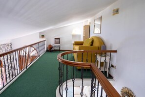 A staircase with a green carpet, a yellow sofa, and a wooden railing.