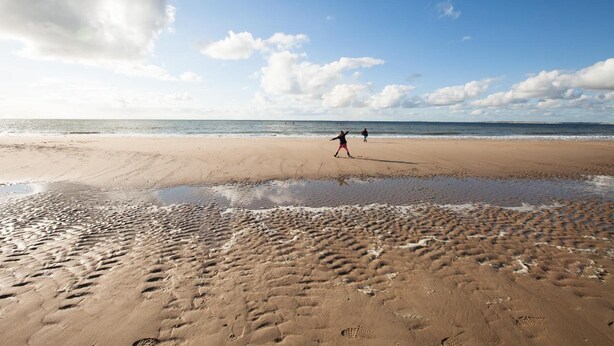 A beach with footprints and two people walking. - Het Zoete Peerd (Groede)