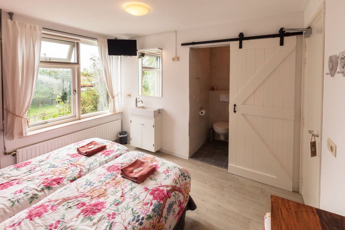 A bedroom with a bed, a window, a bathroom, and a sliding door.