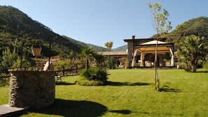 A rustic building with a wooden deck and a stone structure in the foreground. - Le Macine del Confluente (Badalucco)
