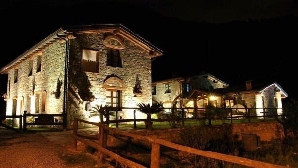 A stone building with multiple windows and a wooden fence in front. - Le Macine del Confluente (Badalucco)