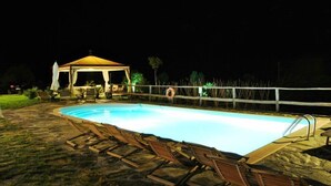A swimming pool with lounge chairs and a gazebo at night. - Le Macine del Confluente (Badalucco)