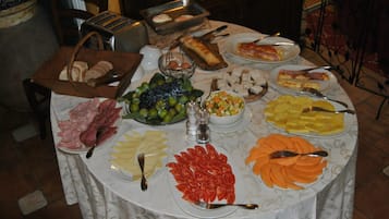 Una mesa de buffet con diferentes alimentos, entre ellos carnes, quesos, frutas y verduras.