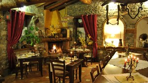 A rustic dining room with a long table set for a meal, stone walls, and a fireplace. - Le Macine del Confluente (Badalucco)