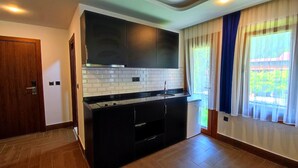 Una cocina moderna con armarios oscuros, salpicadero de azulejos blancos y un amplio ventanal con cortinas.