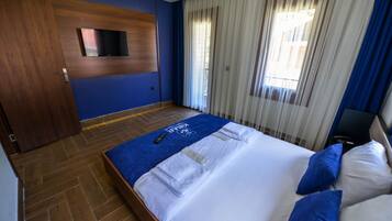 Een hotelkamer met een bed, een aan de muur bevestigde televisie en een raam met gordijnen.