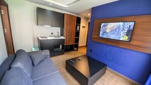 Una sala de estar moderna con un sofá gris, una mesa de centro negra y un televisor instalado en una pared azul.