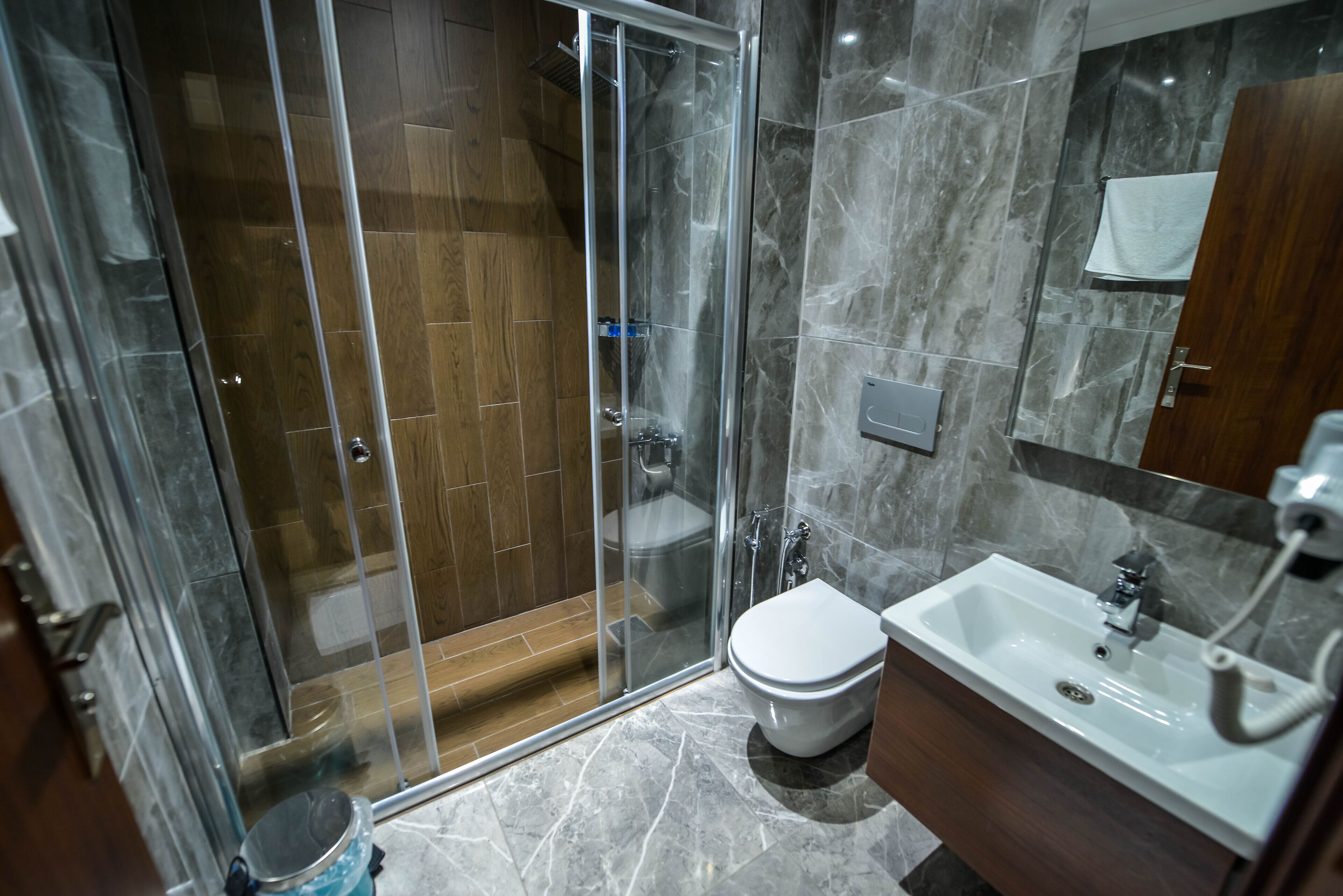 A modern bathroom with a glass-enclosed shower, a white toilet, and a sink with a mirror above it.