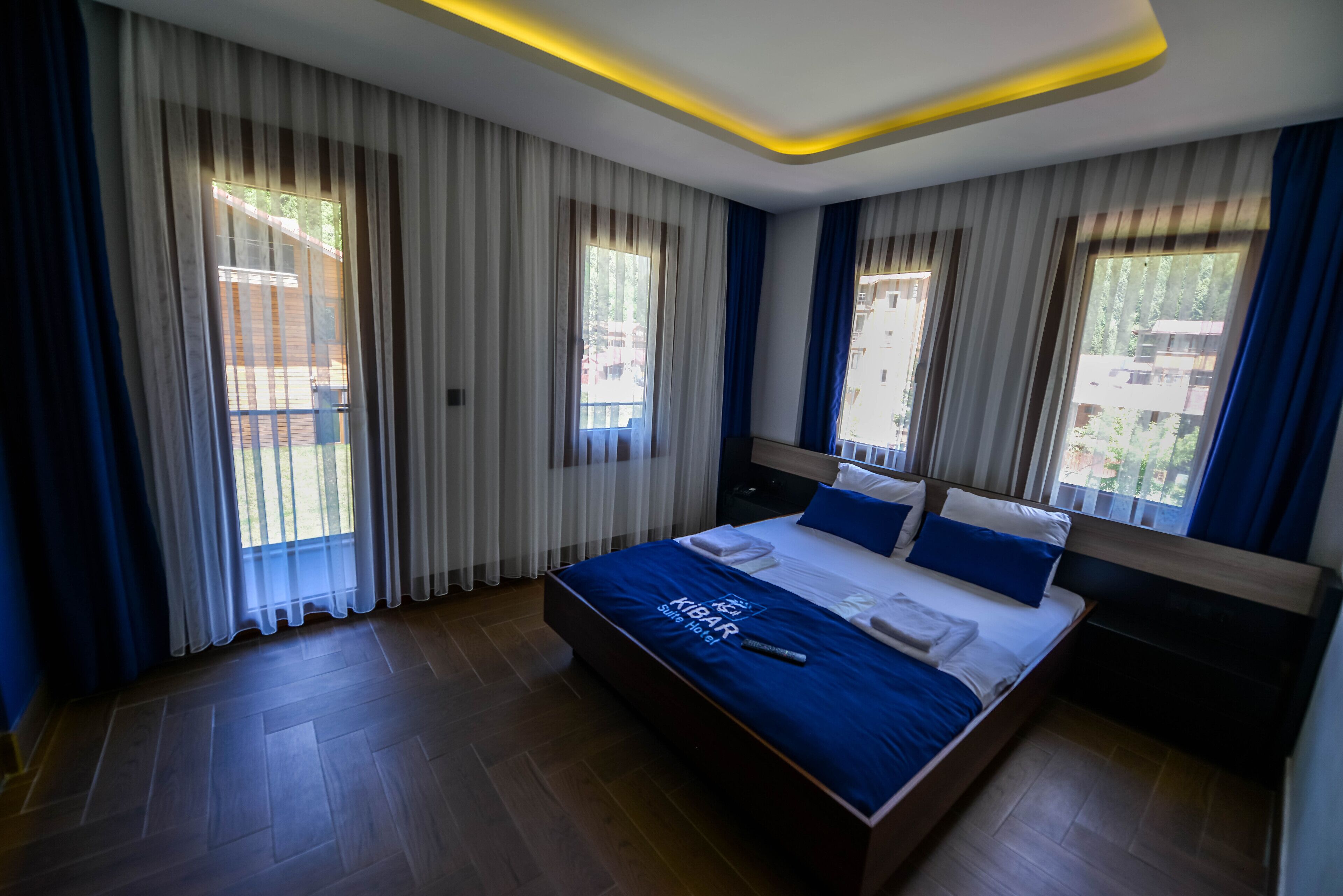 Una habitación de hotel moderna con una cama grande, cortinas y vistas al exterior.