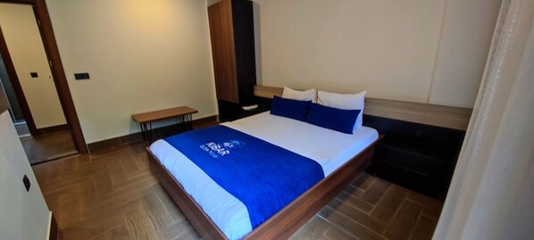 Una cama bien hecha con una colcha azul, un cabecero de madera y un banco al lado.
